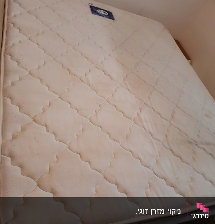 מזרן לבן עם כתמים קלים על מיטה